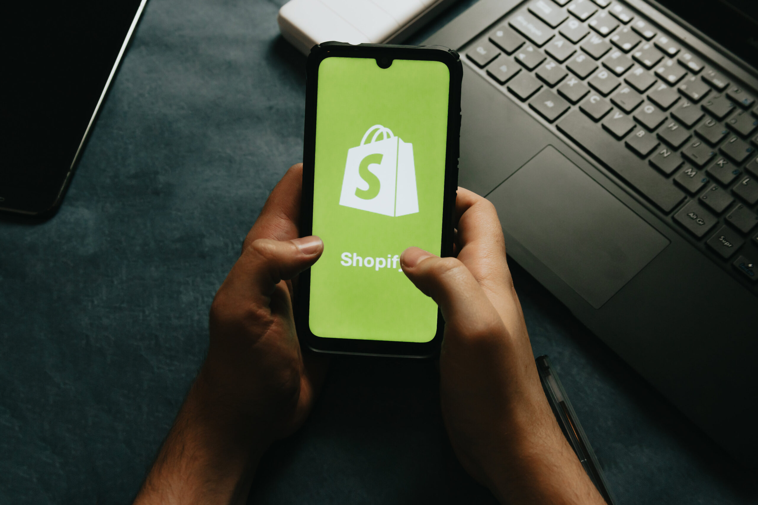 hands-holds-a-cell-phone-showing-the-shopify-logo (1) website design company near me